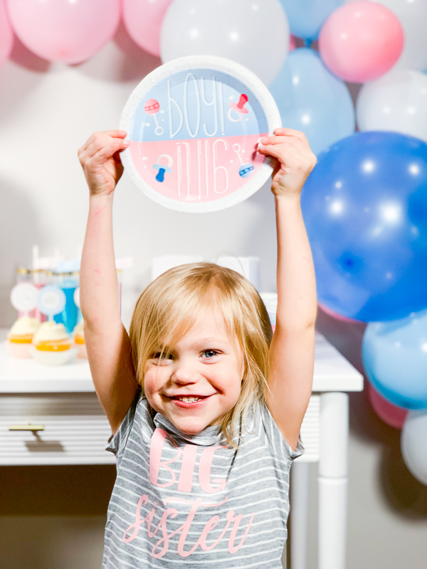 Big Sister holding Gender Reveal Plates - Gender Reveal Party Ideas by Pineapple Paper Co.
