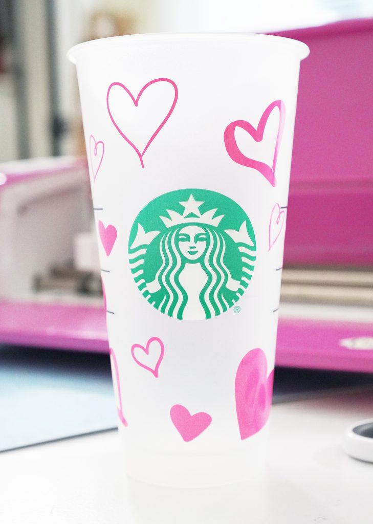 Pink Color Changing Vinyl Hearts on Starbucks Plastic Cup in front of Cricut Machine