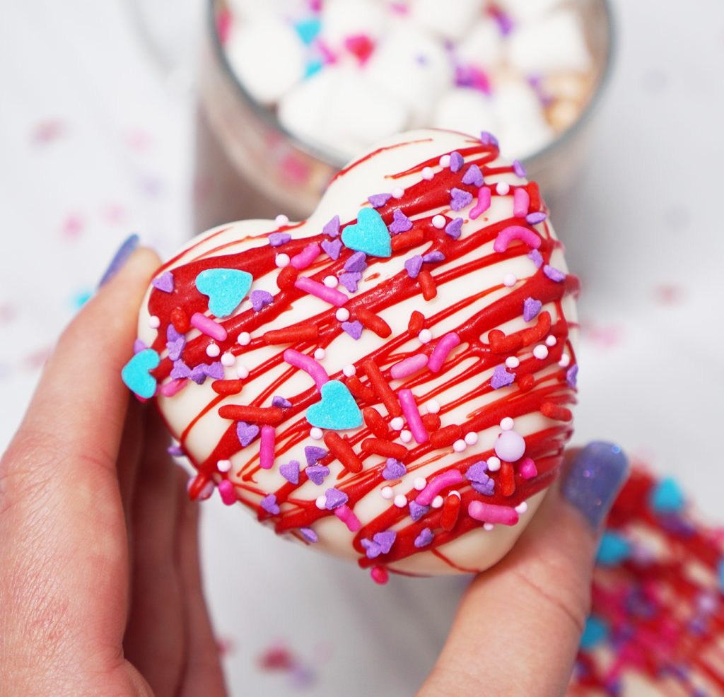 Hand holding Heart shaped Hot Chocolate Bomb for valentine's Day