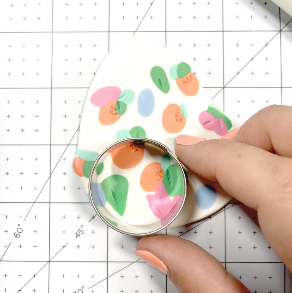 using circle cookie cutter on floral polymer clay slab to make earrings