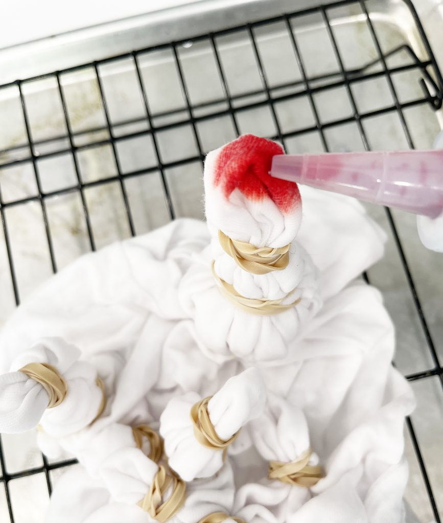 putting red dye with squeeze bottle on fireworks sunburst tie dye shirt