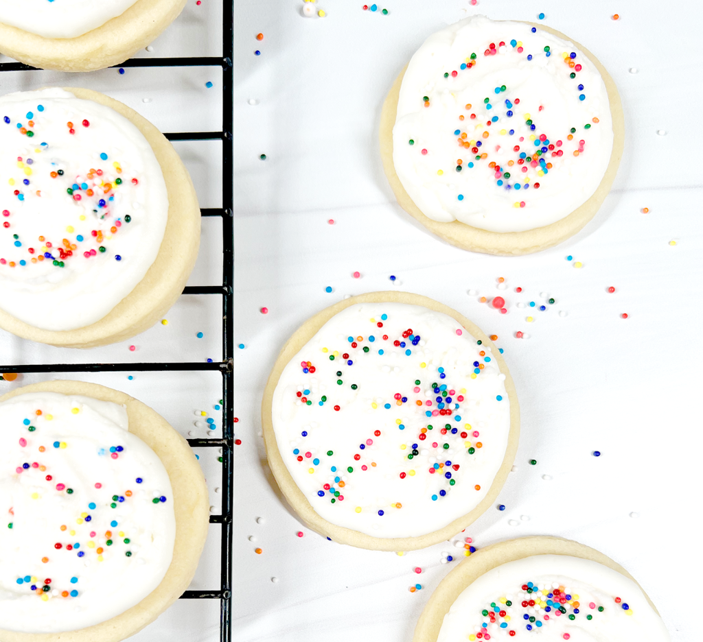cut out sugar cookies with rainbow sprinkles on cooling rack