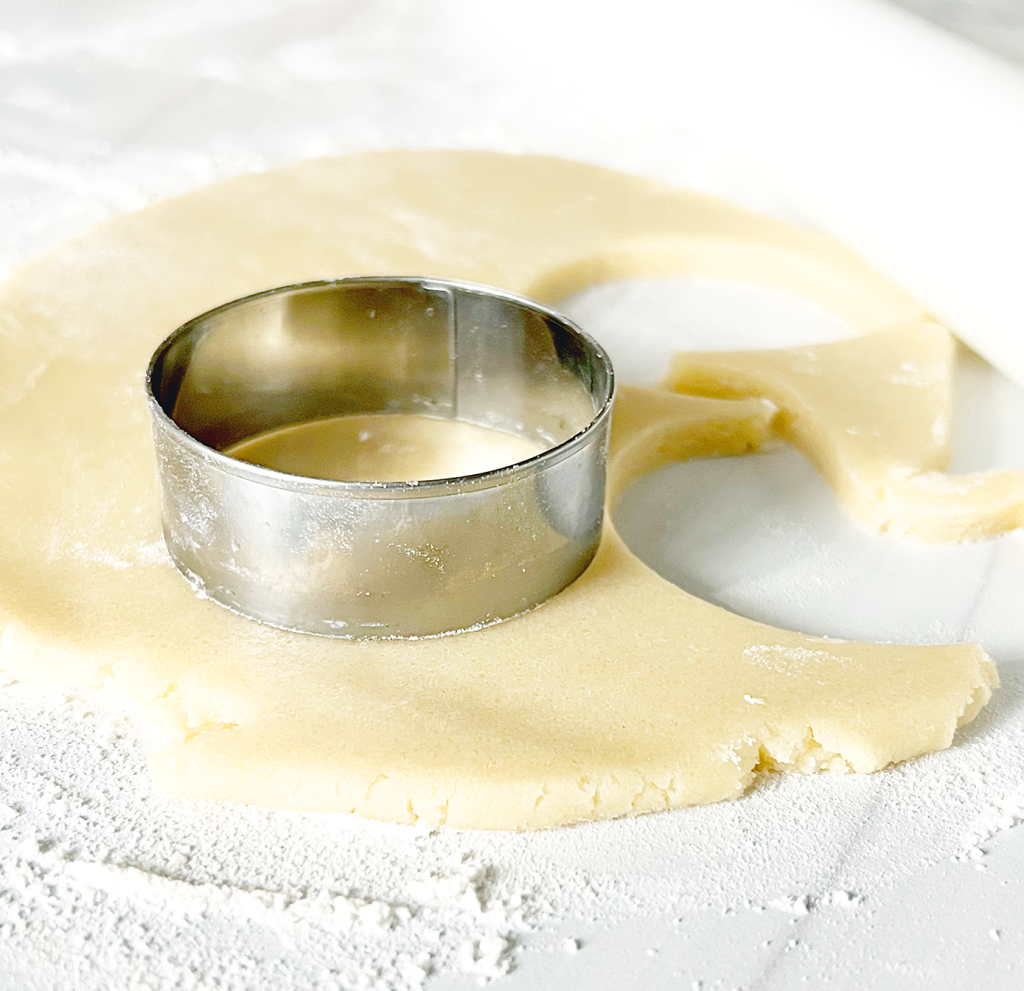 cut out sugar cookies recipe showing round cookie cutter and rolled dough