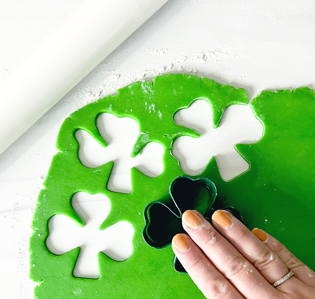 green cookie dough with cut out shamrocks and shamrock cookie cutter
