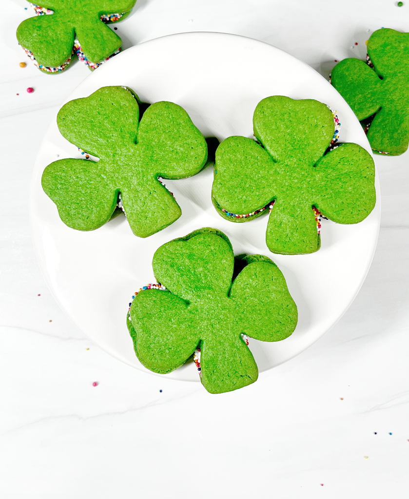 shamrock cookies with rainbow sprinkles on cake stand