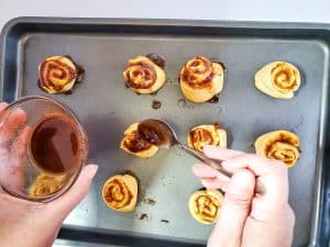 putting icing on pumpkin pie crescent roll pinwheels with a spoon