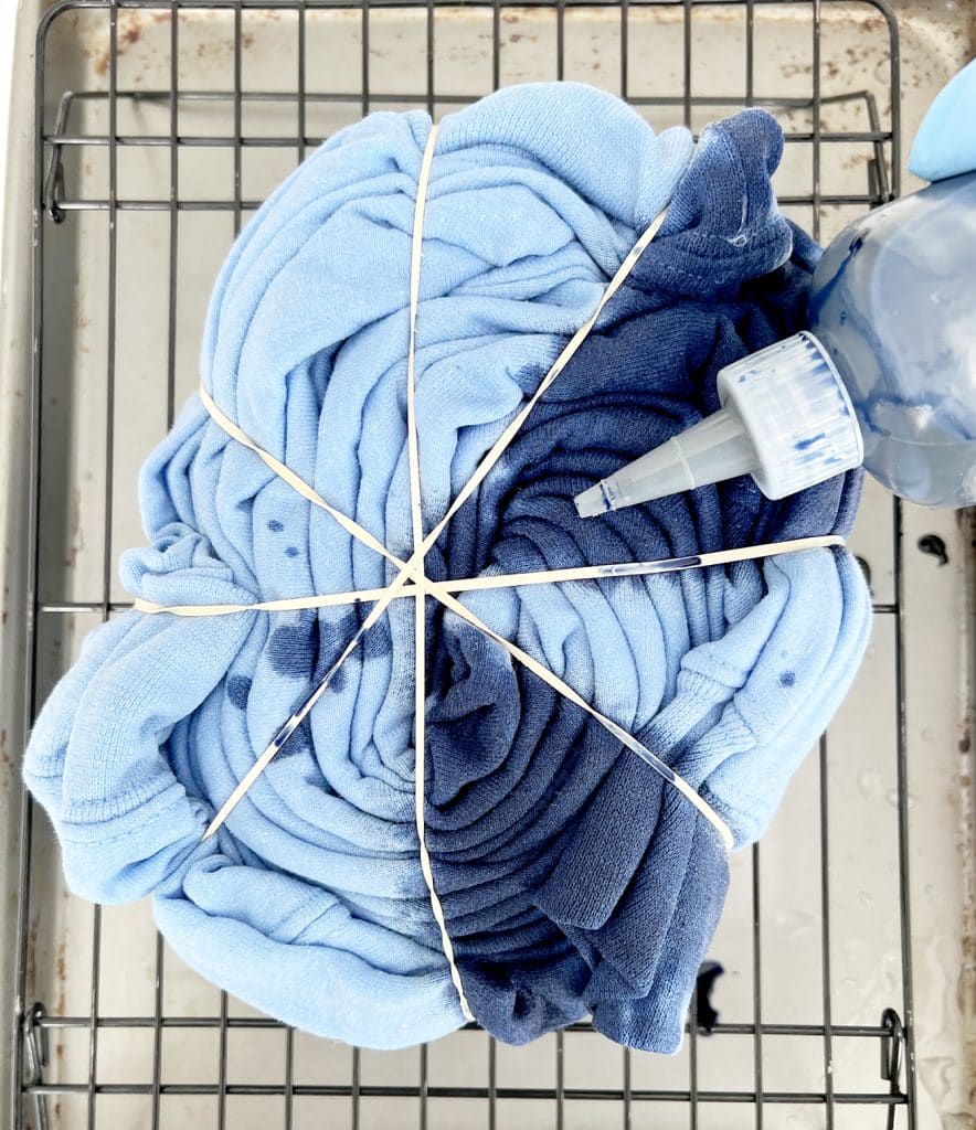 adding blue dye to blue shirt rolled in spiral pattern