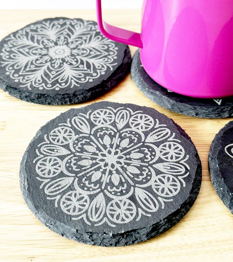 engraved slate coasters with free mandala designs by pineapple paper co. engraved by xtool p2 co2 laser machine with fuschia mug in background