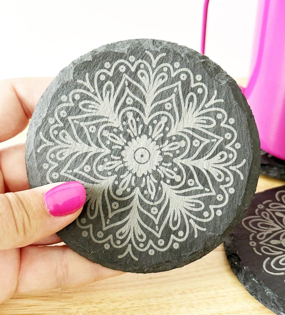 hand holding engraved slate coasters with free mandala designs by pineapple paper co. engraved by xtool p2 co2 laser machine